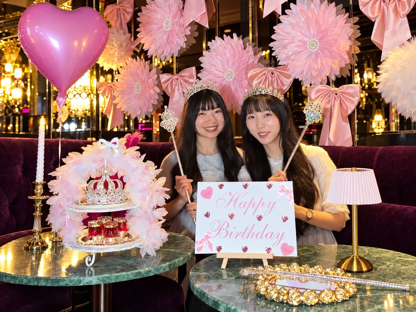 兩位女生在 Salud Taipei 粉紅蝴蝶結夢幻包廂戴皇冠與女王權杖慶生，桌上有雙層蕾絲生日盤與愛心氣球